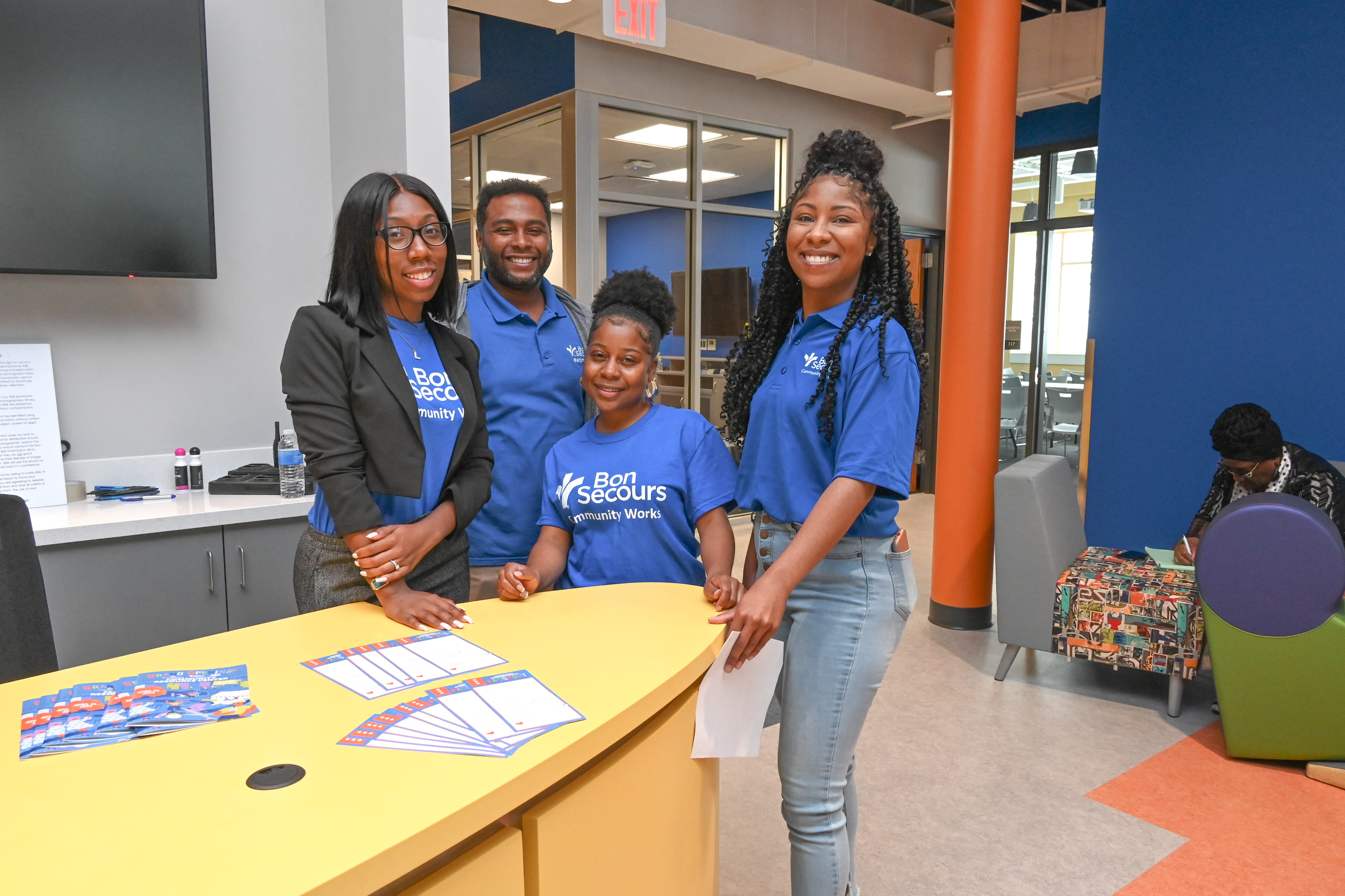 four individuals in Bon Secours Community Works tshirts pose around table