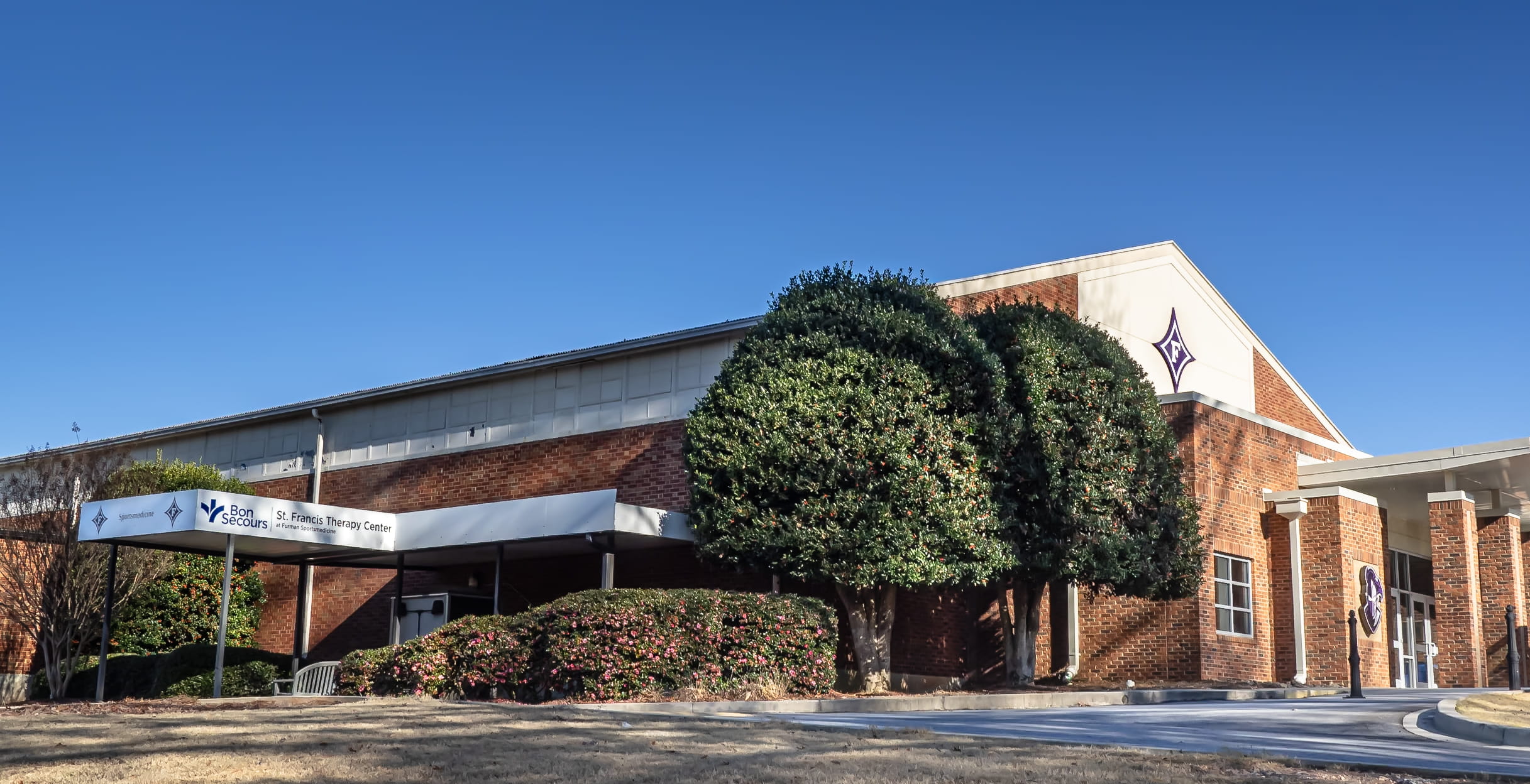 Covered entrance to the therapy center in a large brick building.