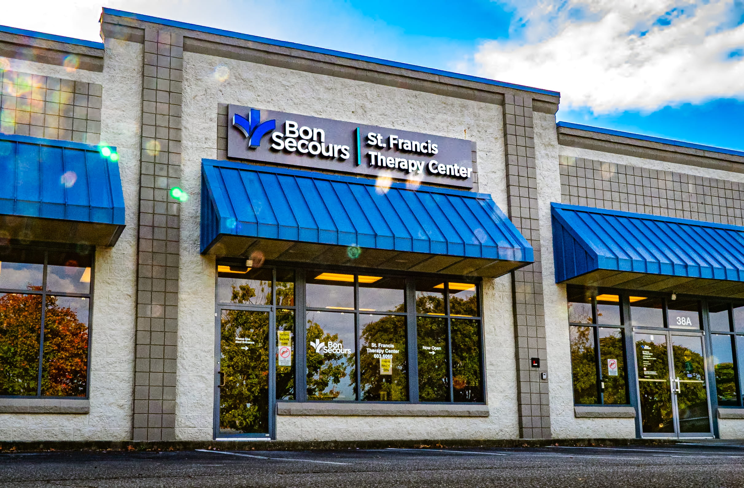 Entrance to the Therapy Center. Grey stucco, brick trim and blue awnings.